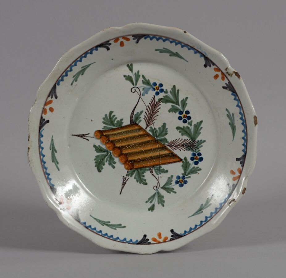 Null ǞǞǞ
一个多色陶盘，上面装饰着箭、弓和箭筒，周围有花环。
18世纪末和19世纪初
直径23厘米
12点和15点之间的筹码