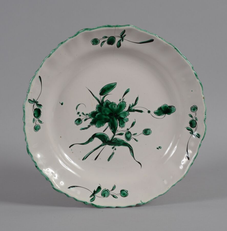 Null 搬家公司
扇形边缘的陶器盘，以绿色单色装饰康乃馨和花茎。
费拉特工作室。
18世纪
直径24厘米
在11小时内5厘米处出现裂缝（板环）。