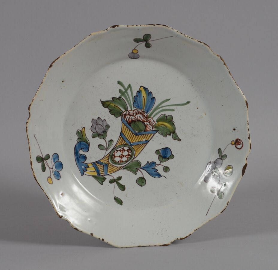 Null 罗歇勒（LA ROCHELLE
一个多色陶器盘子，上面装饰着一个玉米花。
18世纪
直径23.5厘米
在14小时内的一个芯片