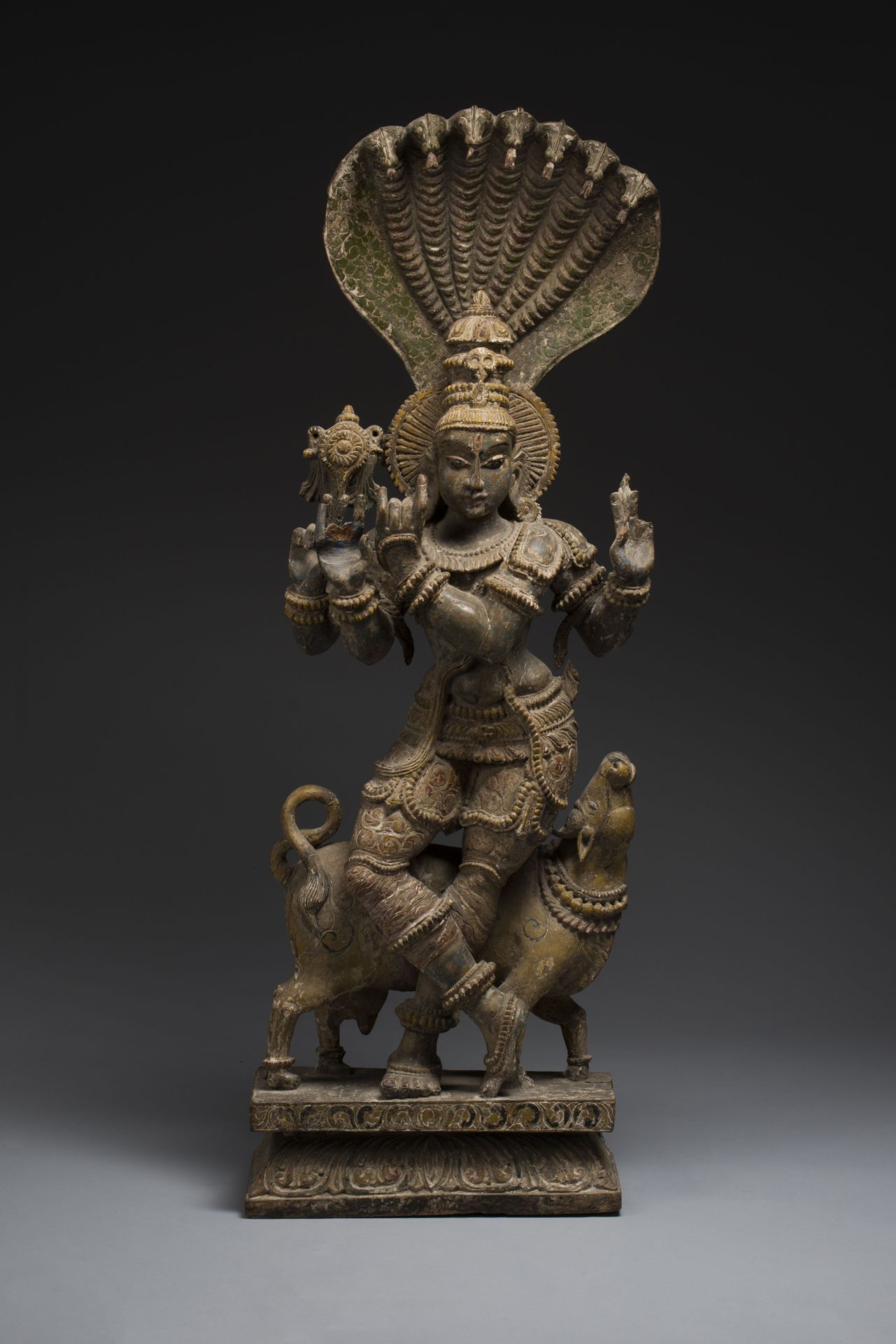 Null 印度，古吉拉特邦。 
重要的多色木制克里希纳雕像，有四只手臂，靠着南迪水牛坐在一个长方形的莲花形底座上。他佩戴着丰富的珠宝，头饰高高盘起，头顶上有一朵&hellip;