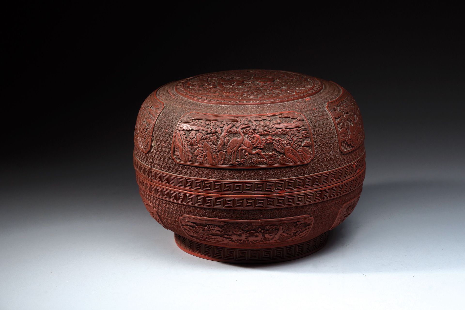 Null 中国，钱龙时期（1736-1795）。 
一个圆形的红漆盒子，盖子上雕刻着一对松树下的鹿，周围有雷文楣，四个底板上交替装饰着一对鹿和鹤的格子背景。边缘&hellip;