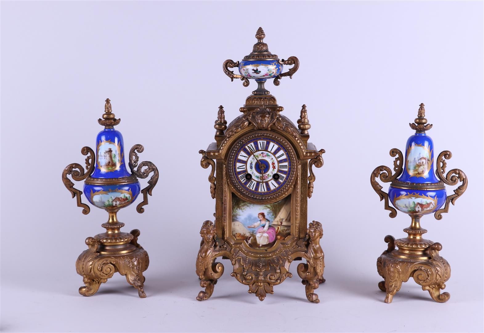 Null 一套铸造时钟，珐琅表盘上有地址："J.B. Burgers/阿姆斯特丹"，下面是一个带有田园风光的瓷牌。大约1880年。
高：38厘米。