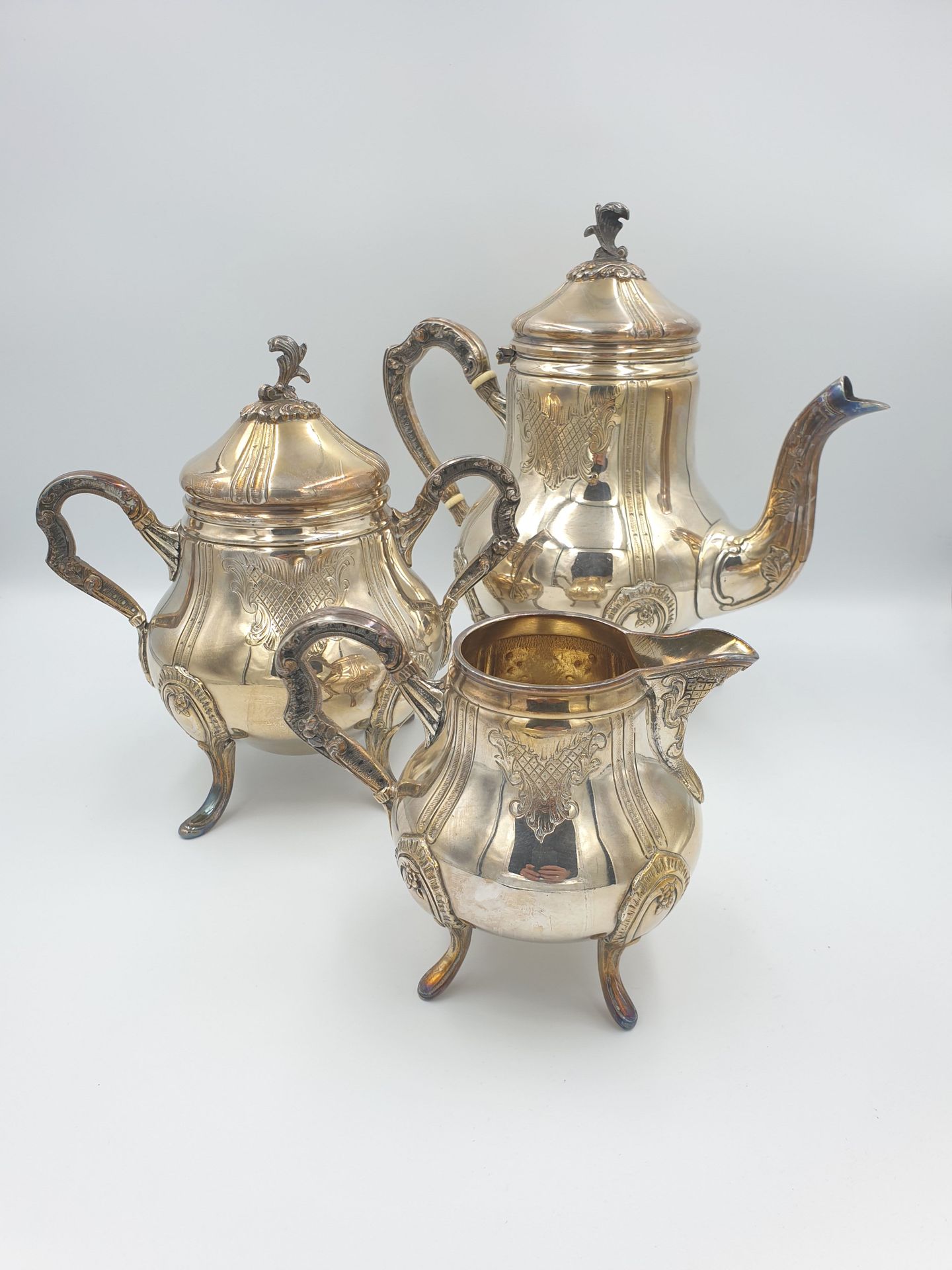 Null 雕刻装饰的镀银茶具，包括一个水壶、一个糖碗和一个牛奶壶

H.23厘米