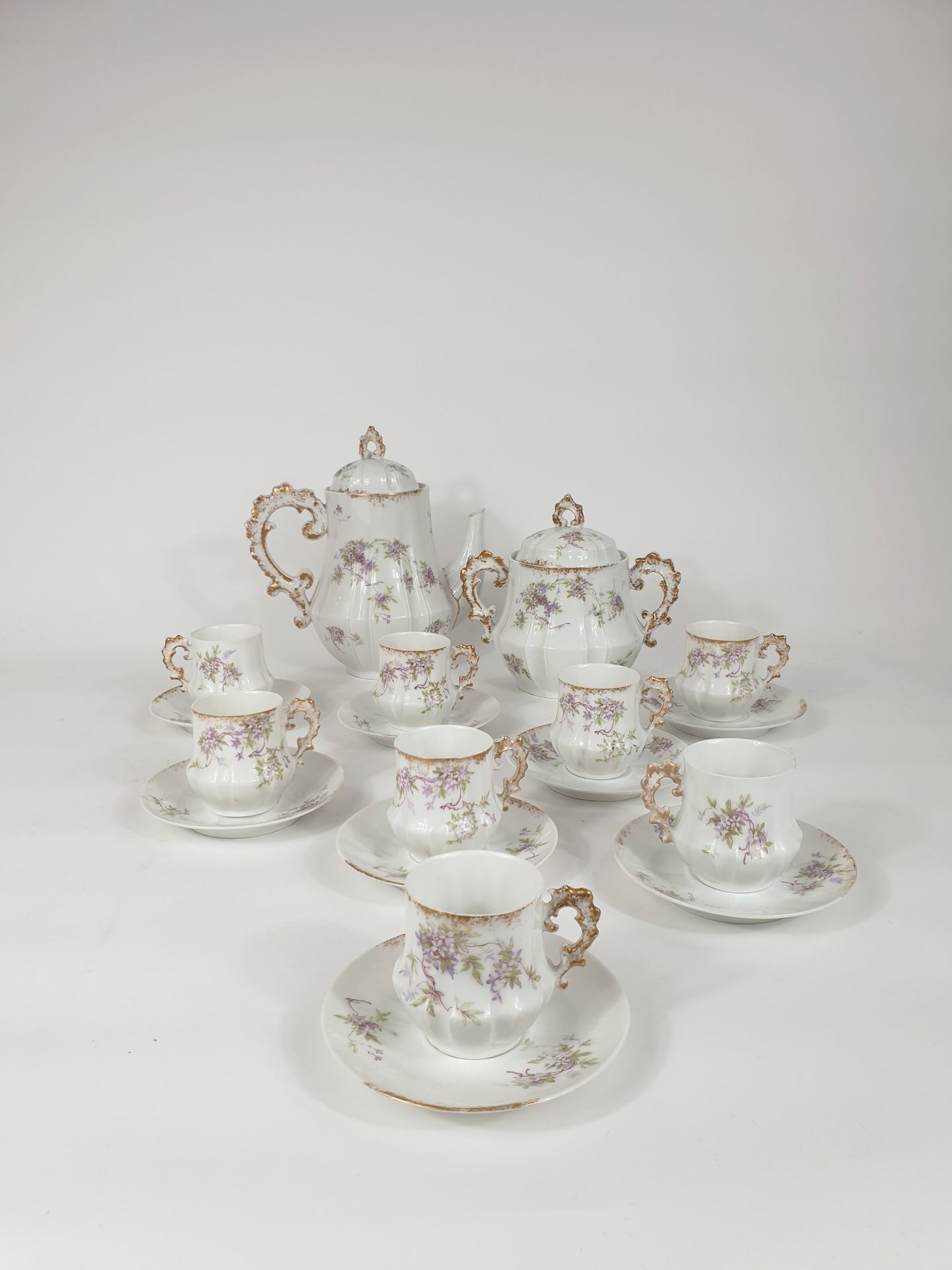 Null 瓷器咖啡套装包括八个杯子和碟子，一个咖啡壶和一个糖碗，上面装饰着枝状紫罗兰花束。
标记 "Aux lions de faïence, Paris, r&hellip;