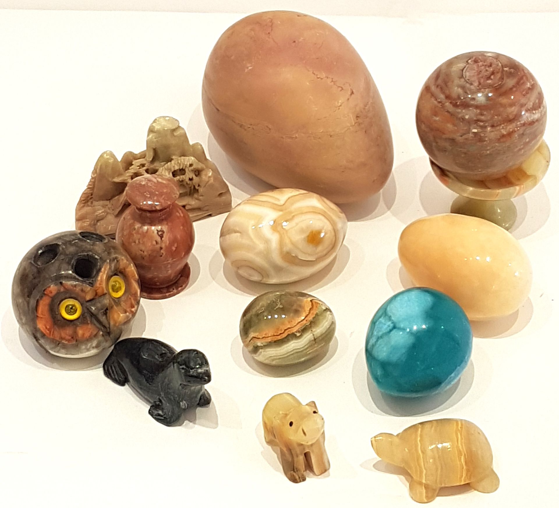 Null 硬石套装包括六个蛋、一个盘子、一个有盖花瓶、一只羽毛猫头鹰、一只乌龟、一头大象、一只海狮和一幅裸石风景画。