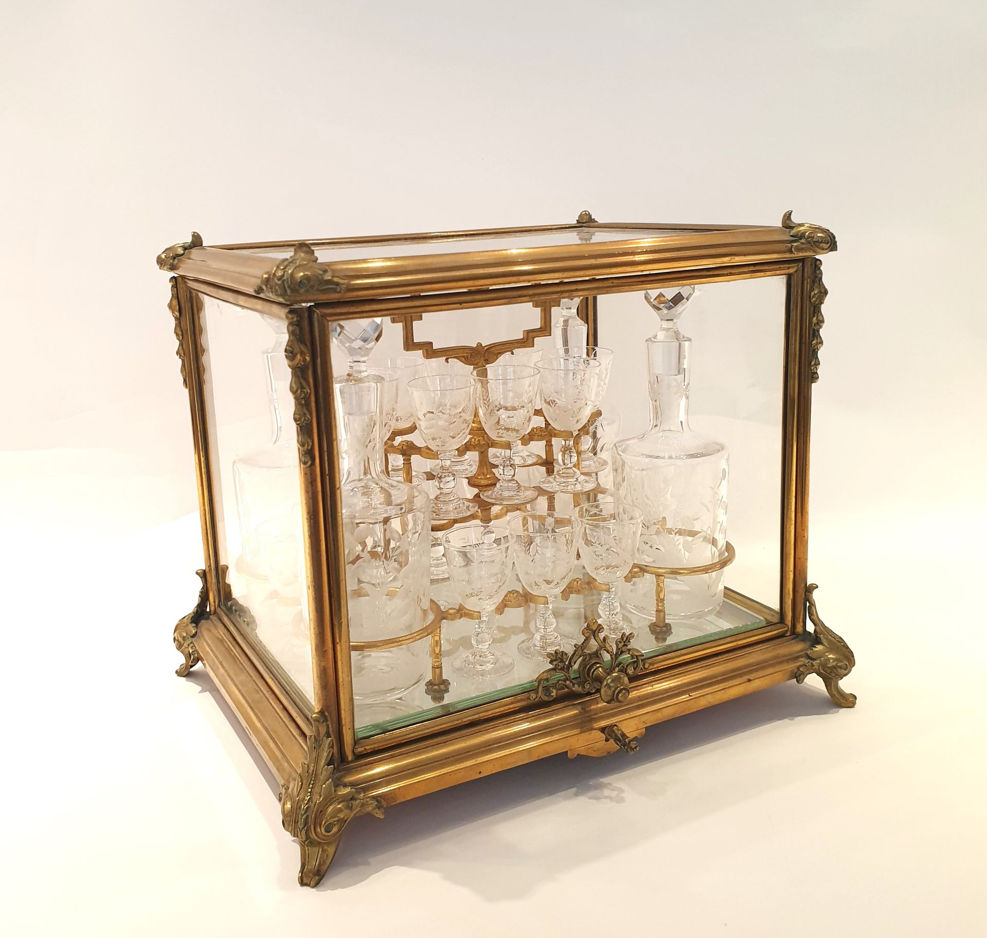 Null 镀金黄铜和雕刻骨瓷利口酒酒窖和玻璃器皿，内有四个雕刻玻璃器皿中的小酒瓶和十六个雕刻花朵和叶子的小水晶杯。
十九世纪 
29 x 34 x 27 厘米