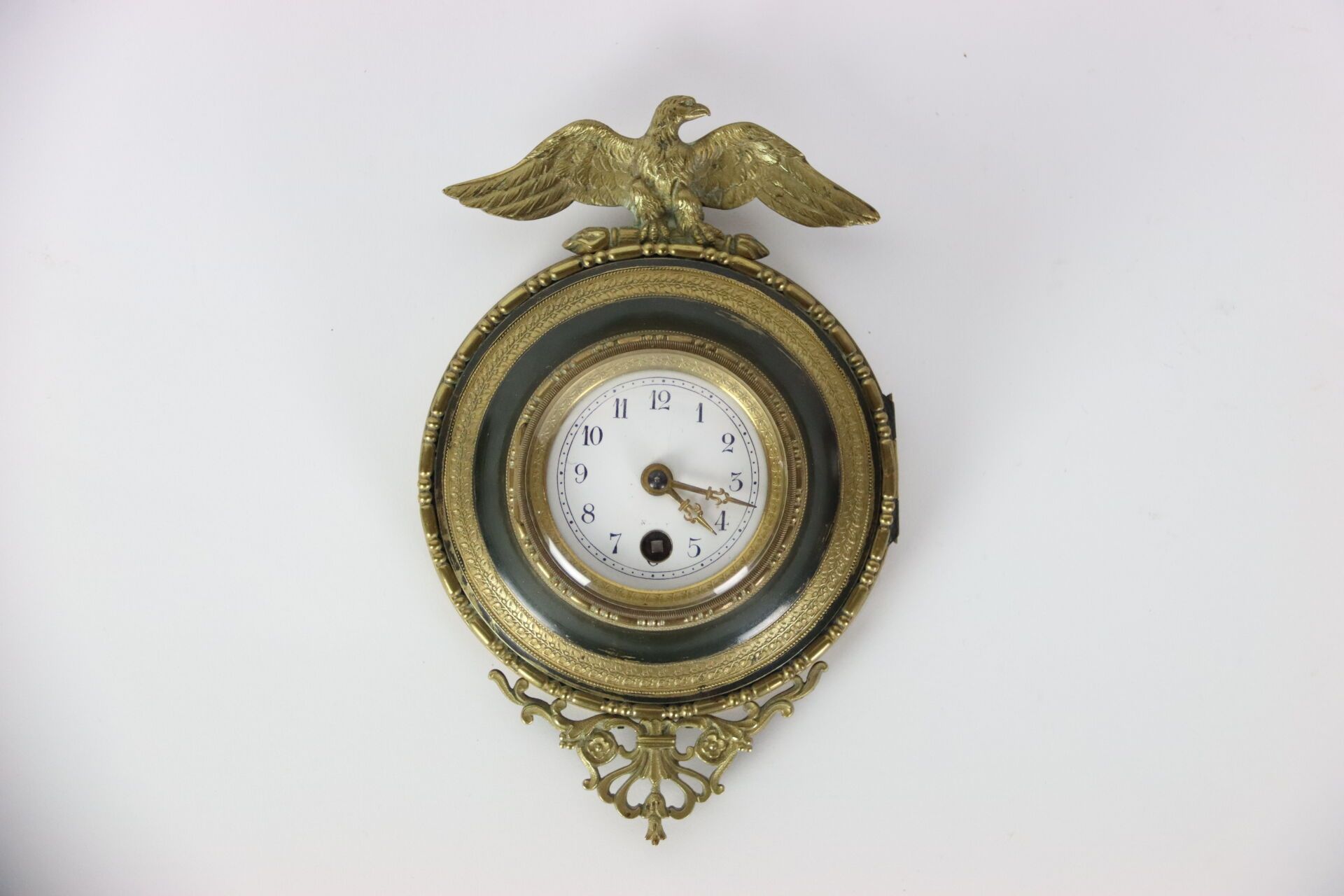 Null 小型圆形壁挂时钟，采用锈蚀金属板制成，顶部有一只雄鹰。黑色边框，阿拉伯数字。螺旋式机芯，钥匙上发条。帝国风格。20 世纪作品。尺寸：20 厘米。