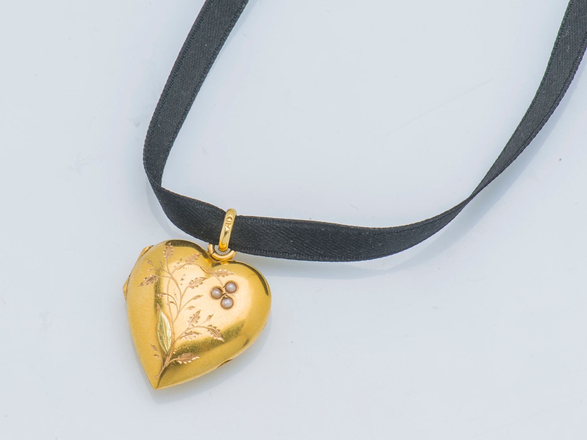 Null 18克拉(750‰)黄金心形照片架吊坠，上面刻有花朵装饰，并点缀有三颗珍珠种子。黑丝绳。

高度 : 3 cm 毛重 : 3,8 g