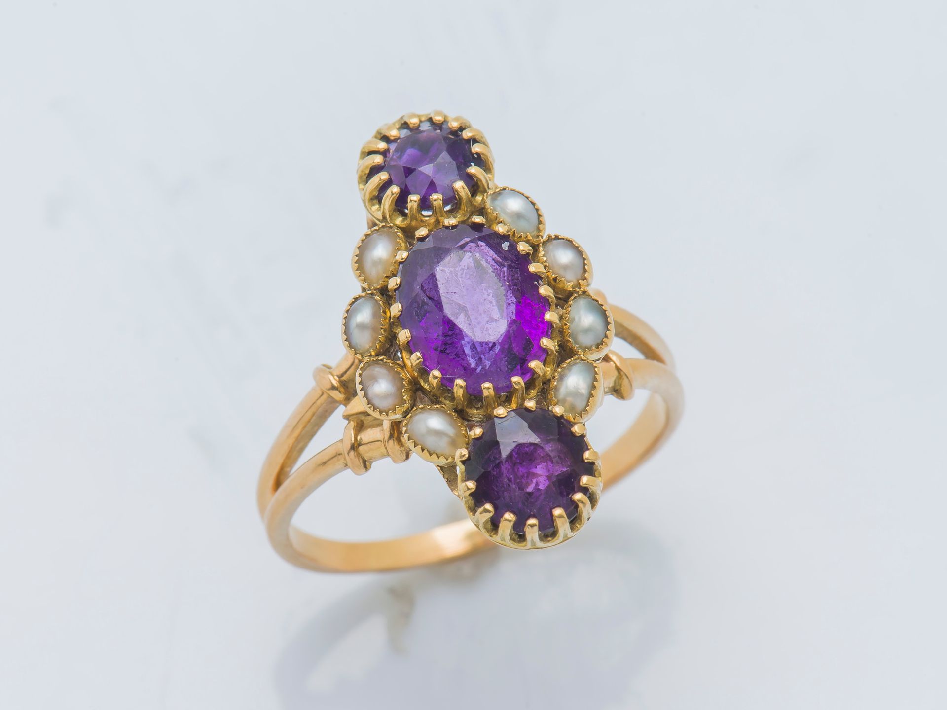 Null 一枚18K黄金（750 ‰）的榄尖形戒指，镶嵌着一个椭圆形的紫水晶，周围有珍珠种子，并有两个圆形紫水晶的框架。19世纪的法国作品，金匠的标记难以辨认。&hellip;