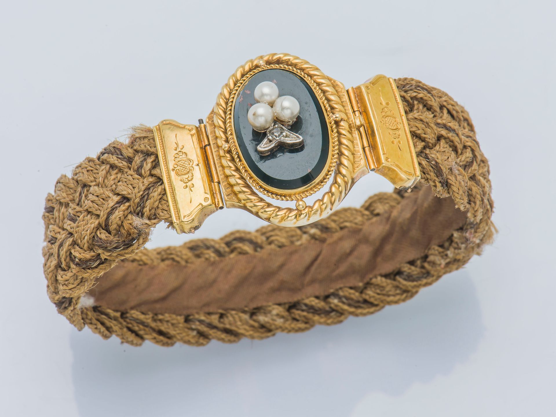 Null 编织的发带手镯，18克拉（750‰）黄金的扣子上镶嵌着一个椭圆形的血碧玉，上面点缀着三颗珍珠的三叶草。法国作品，金匠标记不完整，19世纪。

腕部尺寸&hellip;