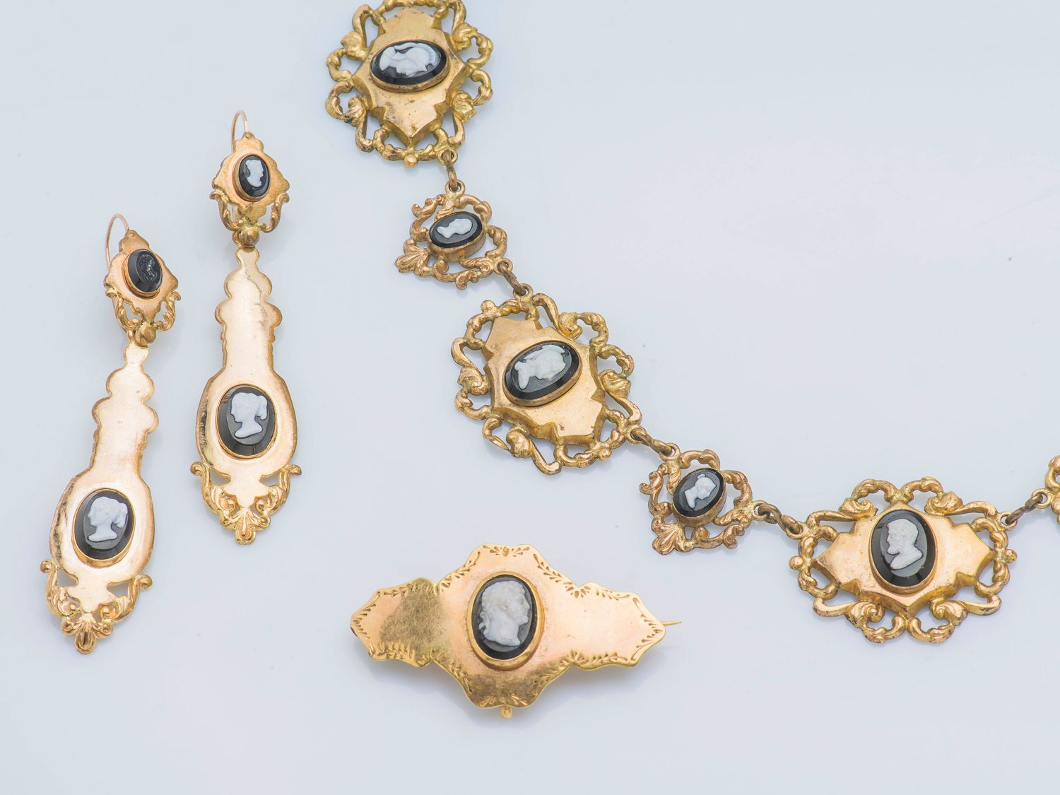 Null 
一套9克拉黄金（375‰）的半成品，包括一条项链，一对耳环和一枚胸针，上面装饰有雕刻着轮廓的卡图。19世纪。




项链长度：41厘米 耳环高度：&hellip;