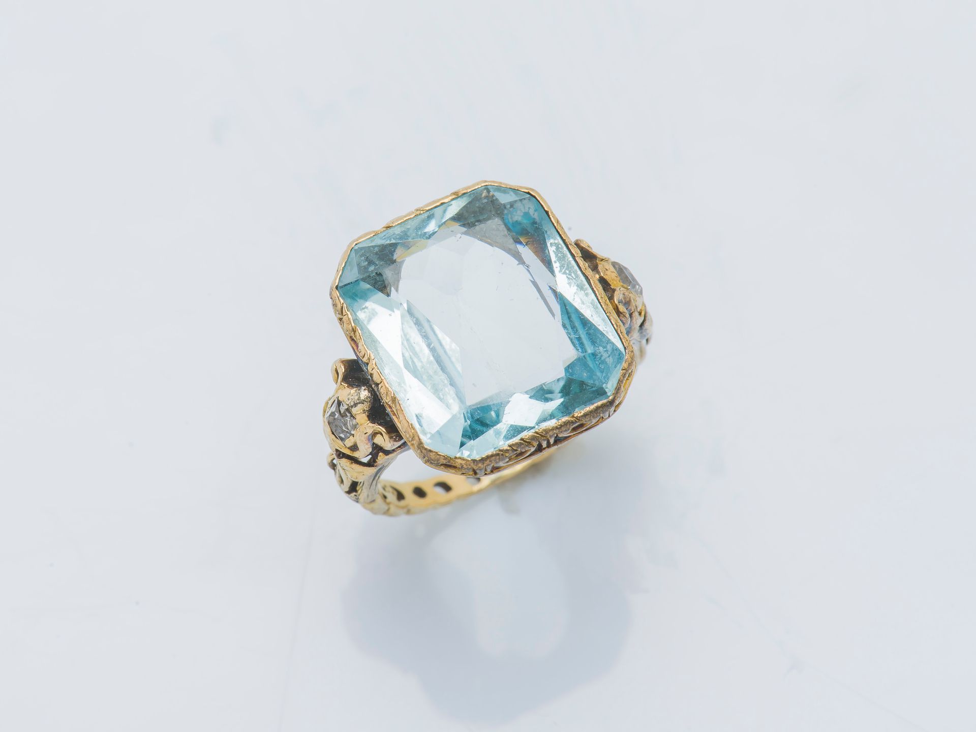 Null 一枚18克拉（750‰）的黄金戒指，镶嵌着一颗约7克拉的长方形海蓝宝石，采用封闭式镶嵌，肩部有两颗方形钻石，篮子和戒指上有精细的凿刻和镂空。19世纪的&hellip;