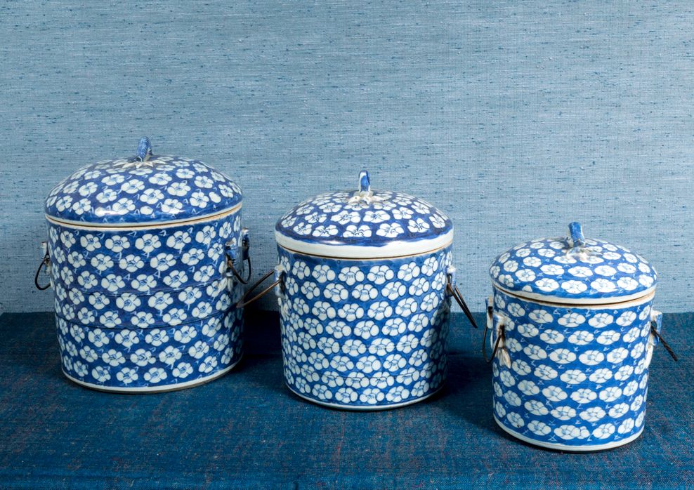 Null 一套三个圆柱形的青花瓷盒，尺寸越来越大，装饰有蓝底白梅花，有两个小把手和一个竹形手柄。

中国，19世纪末。

H.18厘米-20厘米-23厘米。

&hellip;