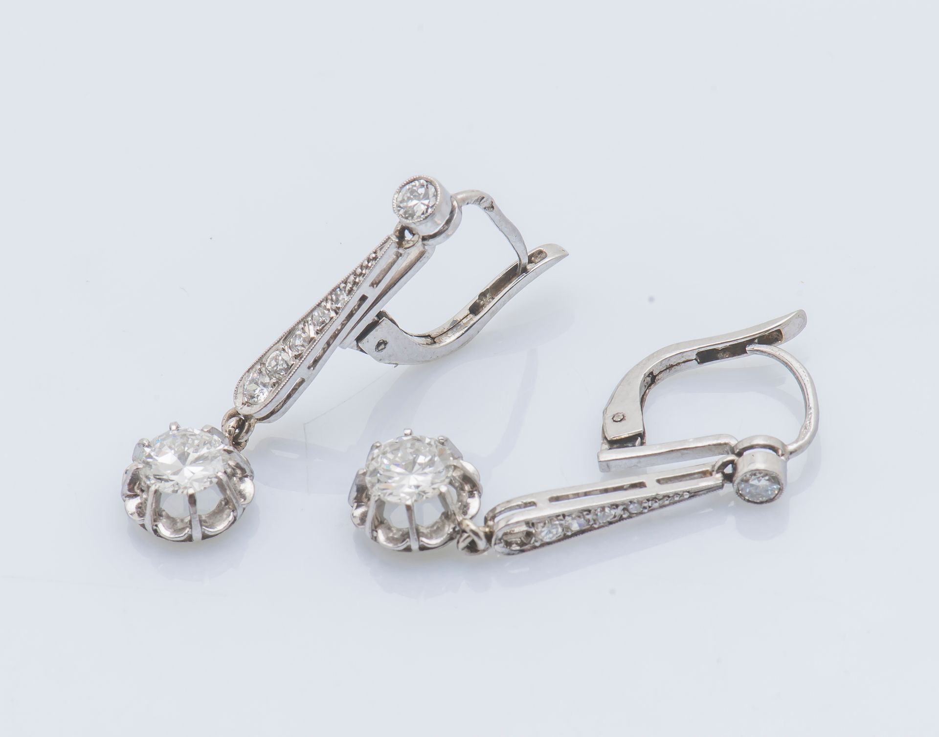 Null 一对18克拉(750 ‰)白金和(950 ‰)铂金耳环，每个耳环都装饰有一排下降的圆钻(缺少一颗钻石)，并支撑着一颗约0.6克拉的明亮型切割钻石作为吊&hellip;