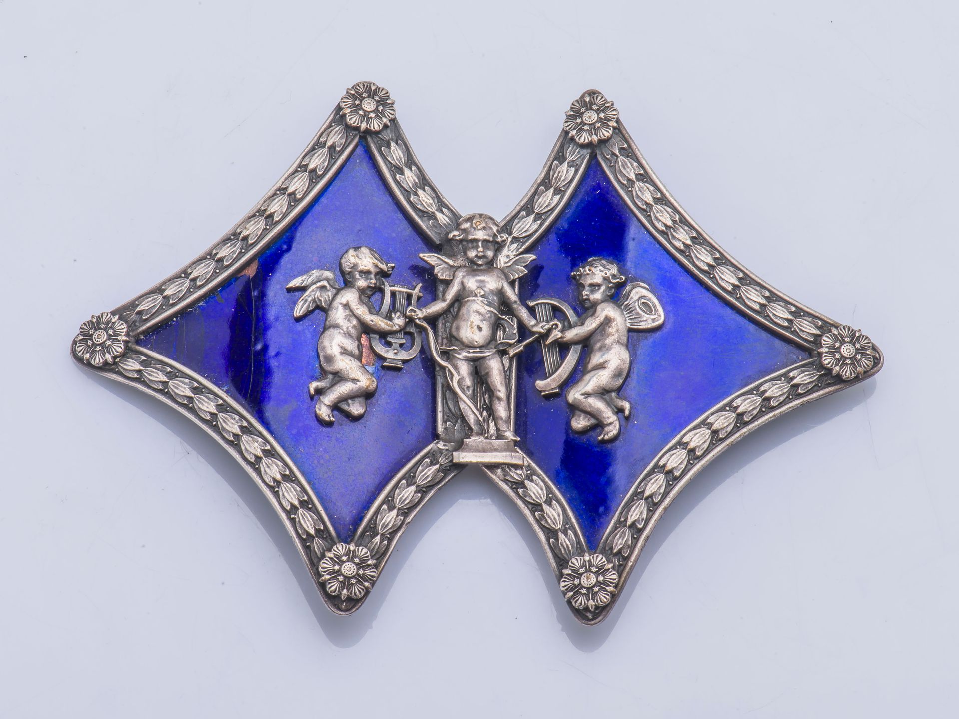 Null 镀银腰带扣，蓝色珐琅背景上有一个丘比特和两个小天使（损坏）。 19世纪作品。

长度：11 cm 高度：7.6 cm 毛重：57.5 g