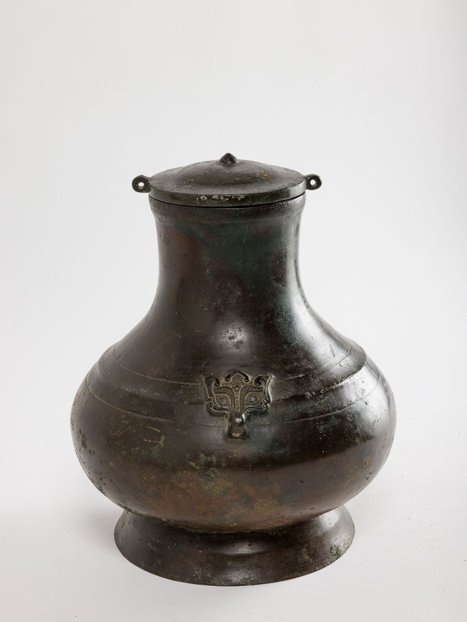 Null 中国，西汉时期（公元前 3-1 世纪）
一件青铜盖胡瓶，圜底，撇足，瓶身饰一圈微浮雕和两个饕餮头。
高：26 厘米

专家：安萨斯-帕皮隆内阁