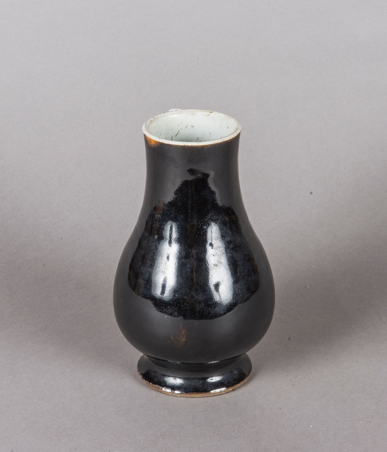 Null 中国 
一个底座上施黑釉的白瓷小花瓶。 
高度：16 厘米