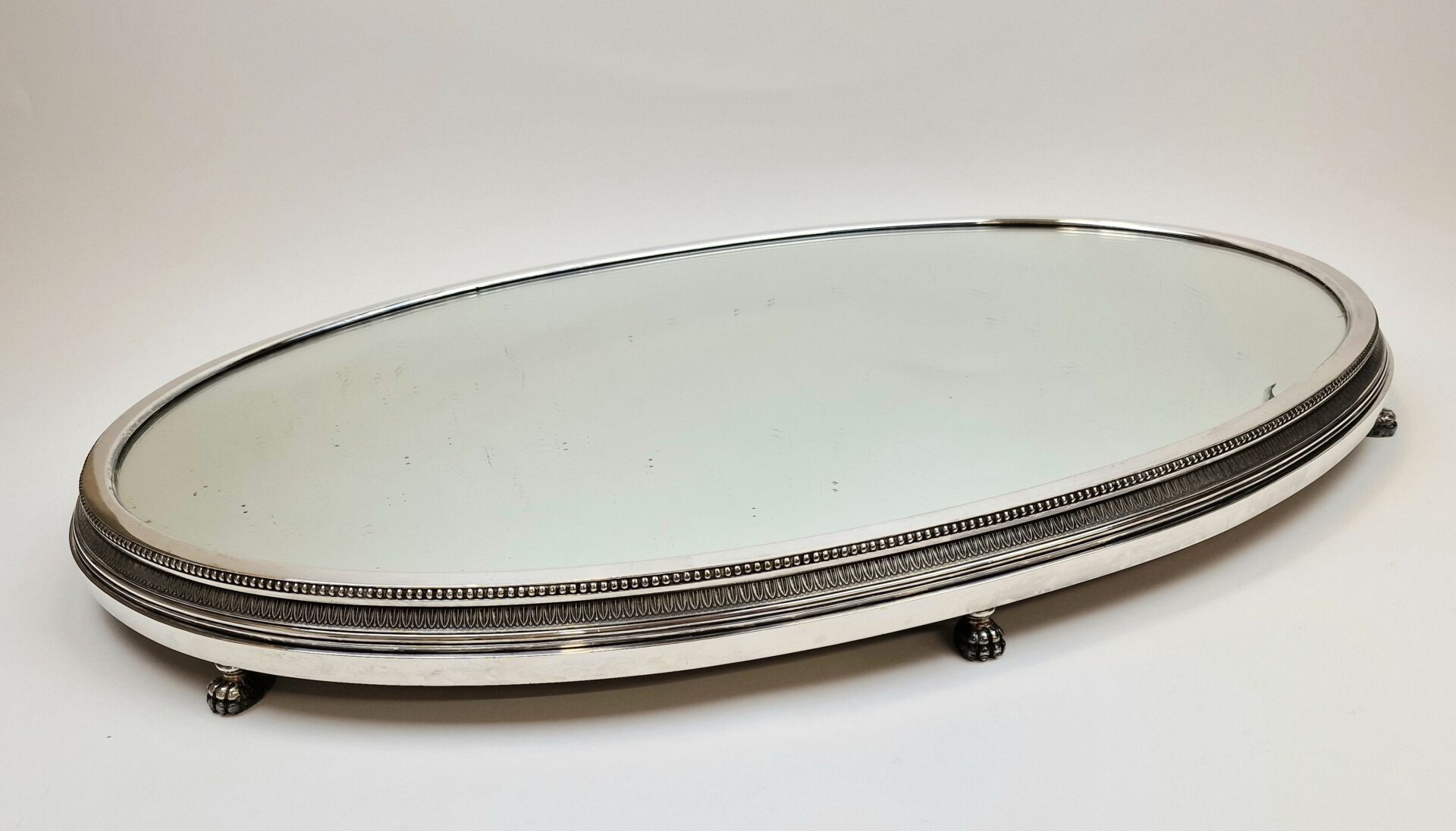 Null A.RISLER & CARRÉ 巴黎店
椭圆形镀银金属桌面，镜面底座镶有一排珍珠，并有四只狮爪支撑。
73 x 50 厘米
(玻璃碎裂）
