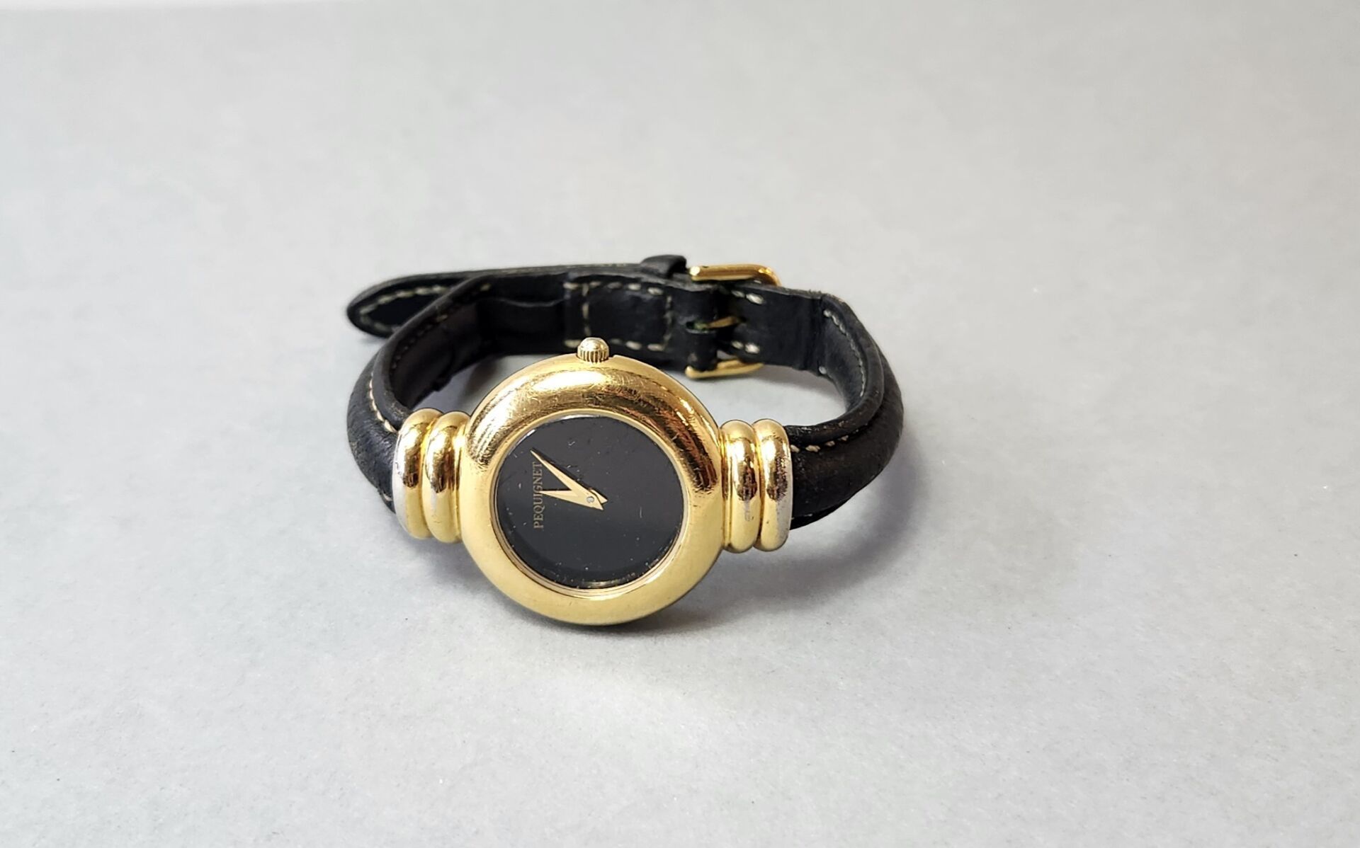 Null @@@ PEQUIGNET
Bracelet montre de dame 
En métal doré
Cadran noir signé 
Bra&hellip;