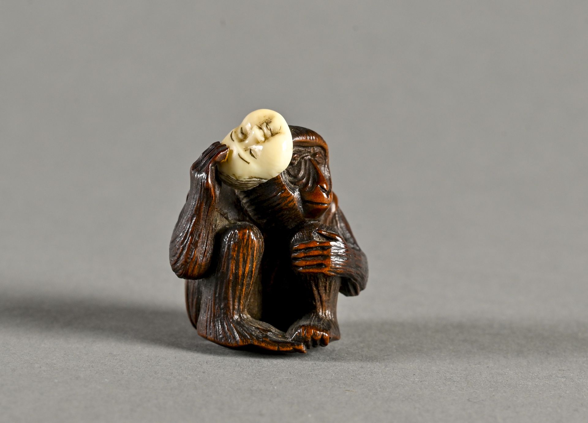 JAPON, Epoque Meiji, 1880 代表猴子的黄杨木网饰，拿着okame的面具

背面有两个himotoshi孔

签名为 "Tai tei"？&hellip;