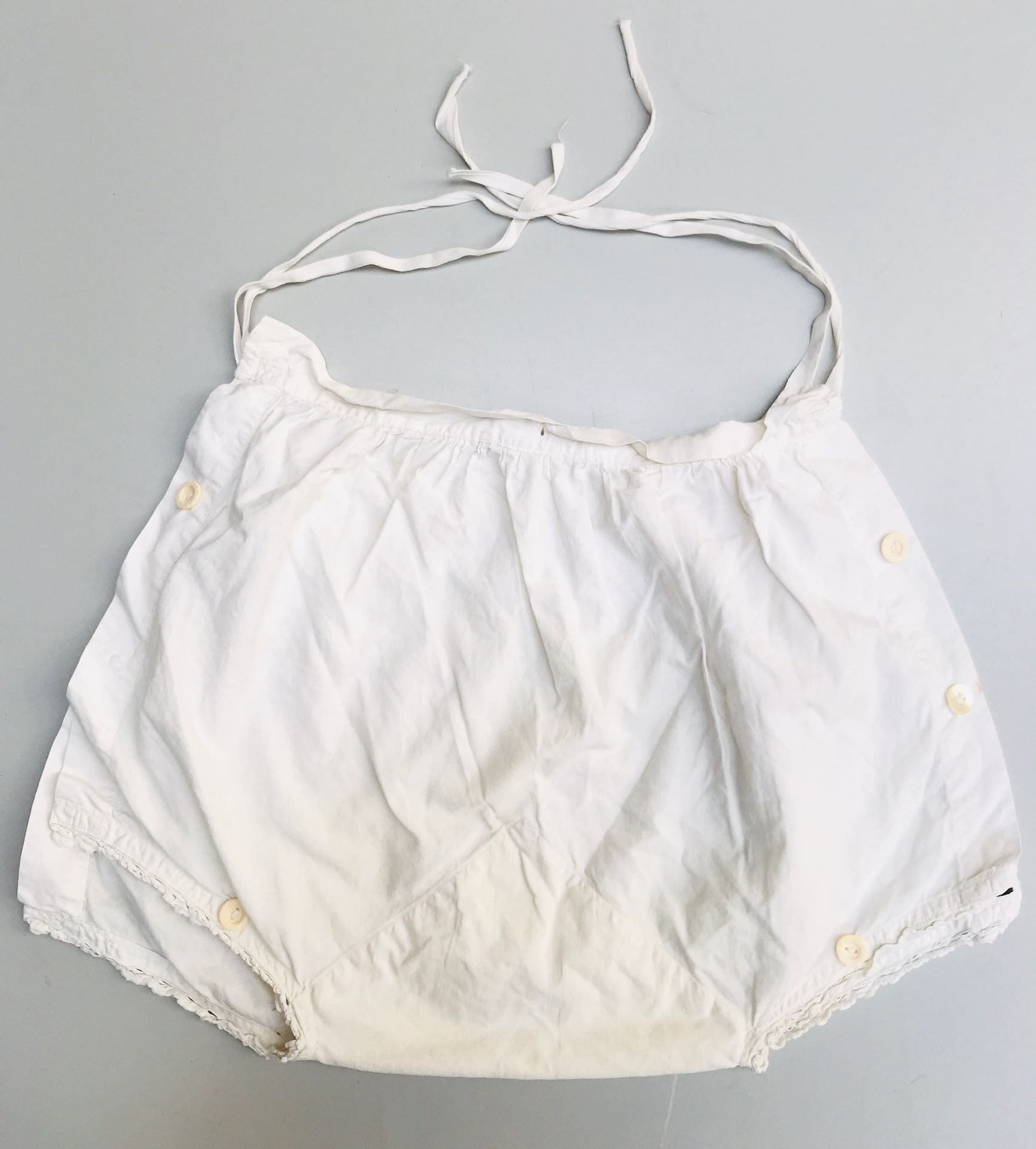 Quatre culottes d'enfant 
白色棉布，有纽扣标签和织物领带，有些是有图案的

磨损和污渍