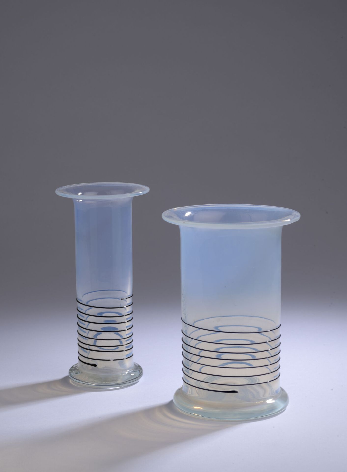 Null 1990年代的意大利作品。

一系列的两个花瓶，采用非常轻微的乳白色玻璃，装饰有优雅的黑色玻璃线环绕结构。

较大的那个的尺寸。H. 19 cm - &hellip;