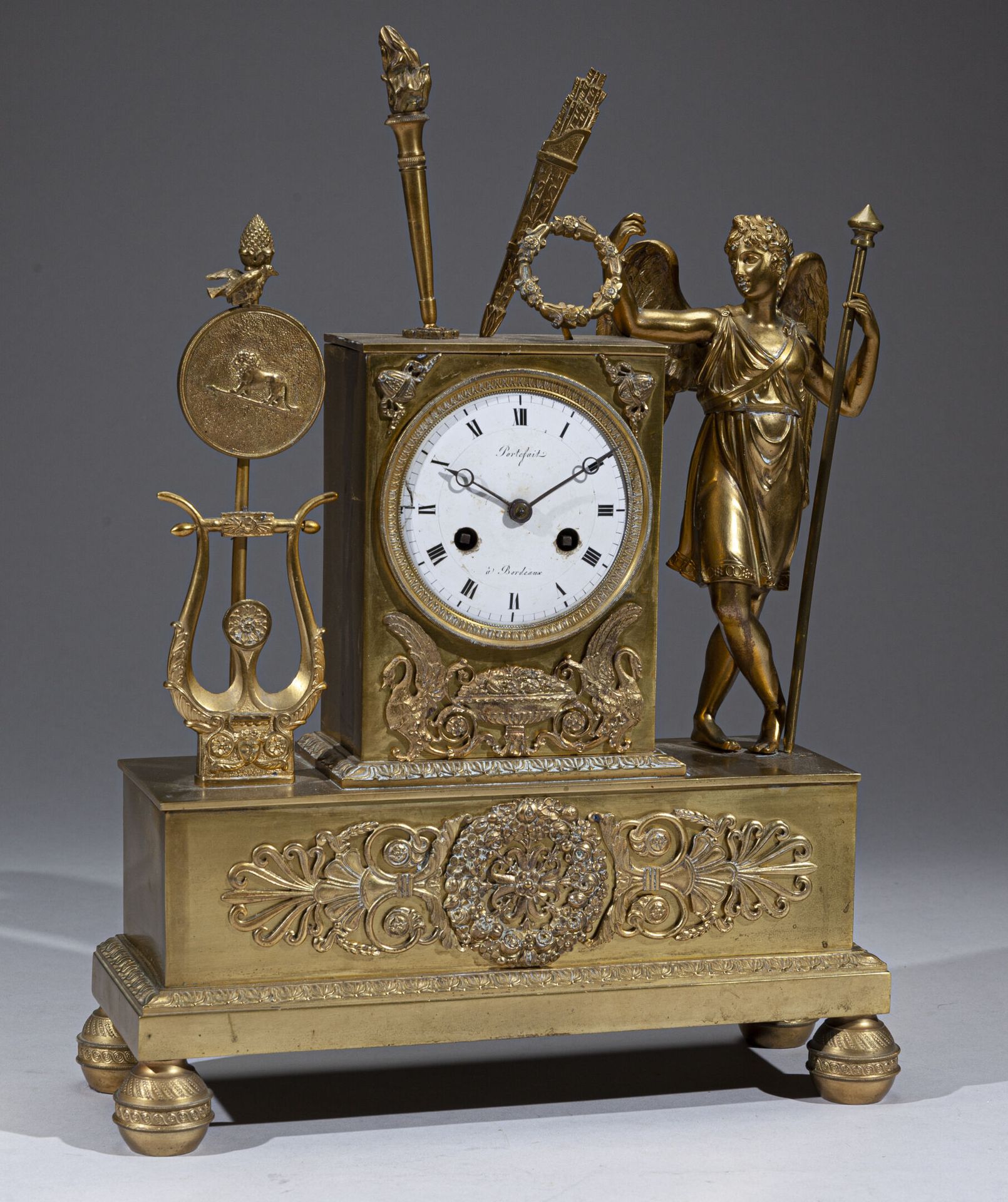 Pendule en bronze doré à figure de génie tenant une lampe, appuyé sur une base s&hellip;