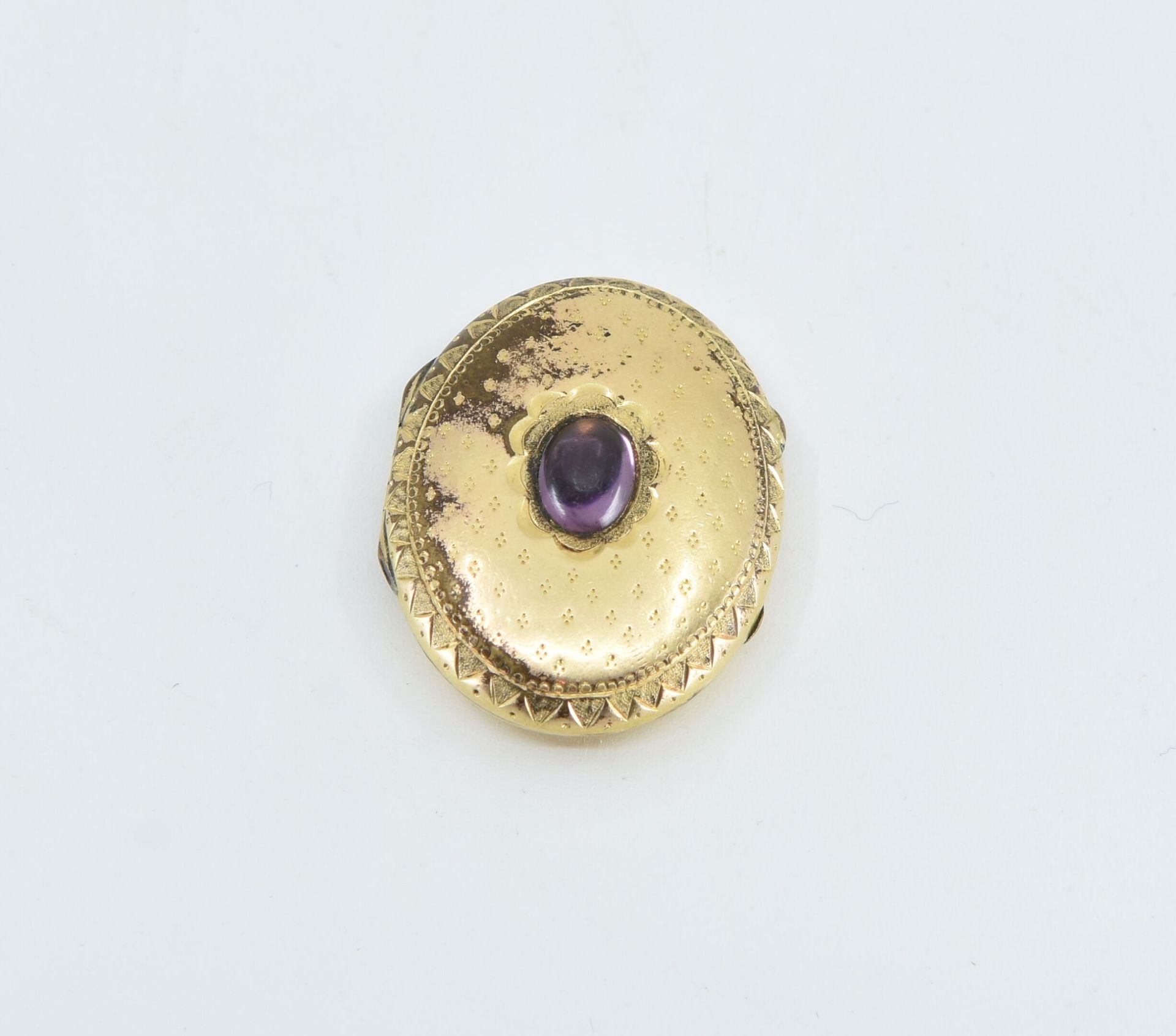 Null 镶有凸圆形紫水晶的鎏金金属吊坠
毛重：7克（玻璃内）。 
遗失扣子 

按指定用途出售的拍品