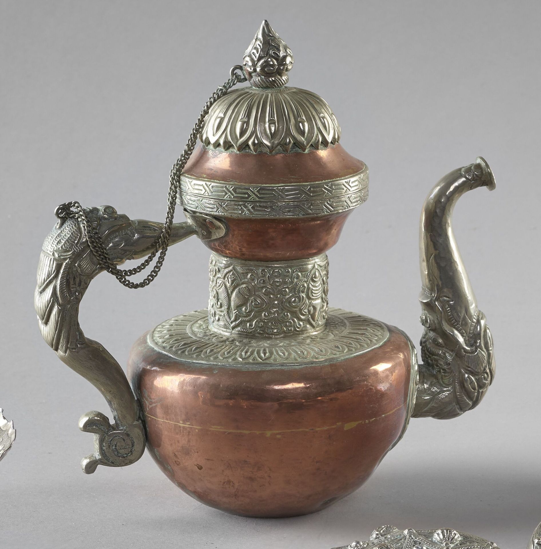 Null 西藏，19世纪末/20世纪初
铜银壶（低标题），装饰有莲花花瓣和叶子，壶把由龙头吐出，壶嘴有一个马卡拉头
H.23厘米 LDM
附有一个铜合金的仪式乐&hellip;