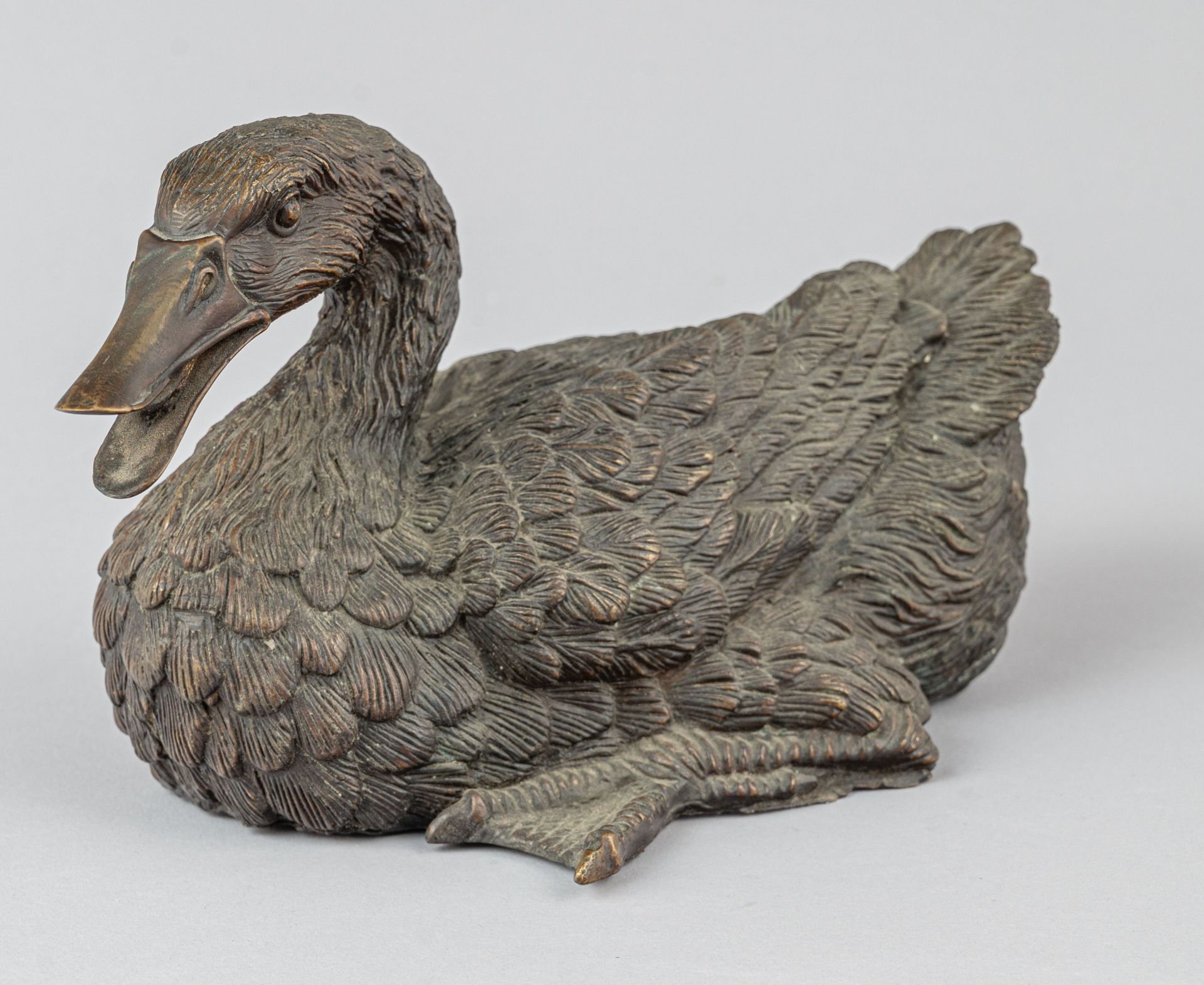 Null 铜鸭，可能是日本明治时期（1868-1912 年）
一只鸭子躺在地上，一条腿伸出，脖子弯曲，嘴张开，羽毛浮雕得很好。
H.16 厘米 - 27 厘米