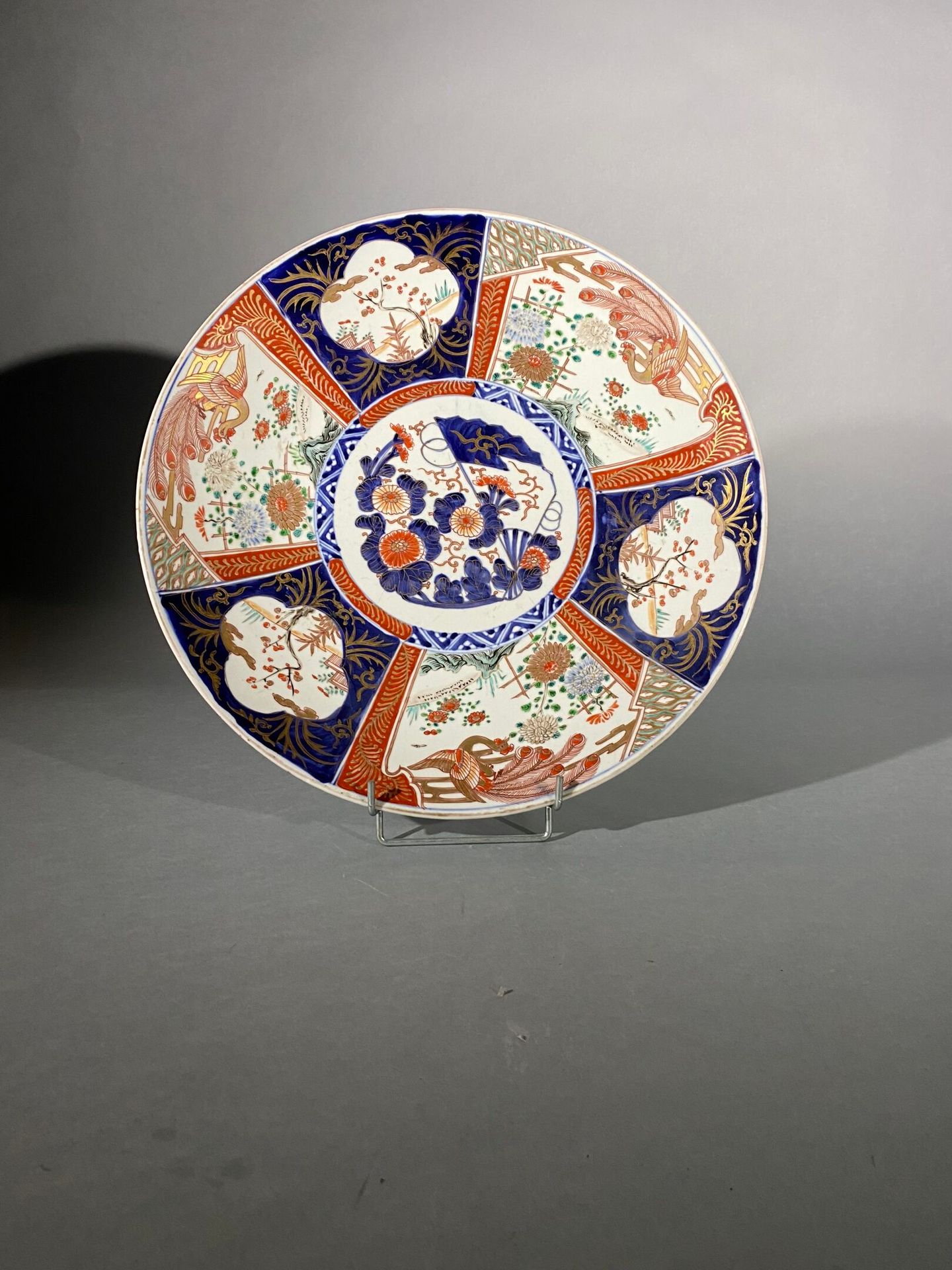 Null 伊万里瓷盘，日本，明治时期（1868-1912 年）
以蓝色釉下彩、多彩珐琅和金色装饰，中间有花朵和扇子，周围是交替出现的凤凰飞翔和梅花盛开的图案。珐&hellip;