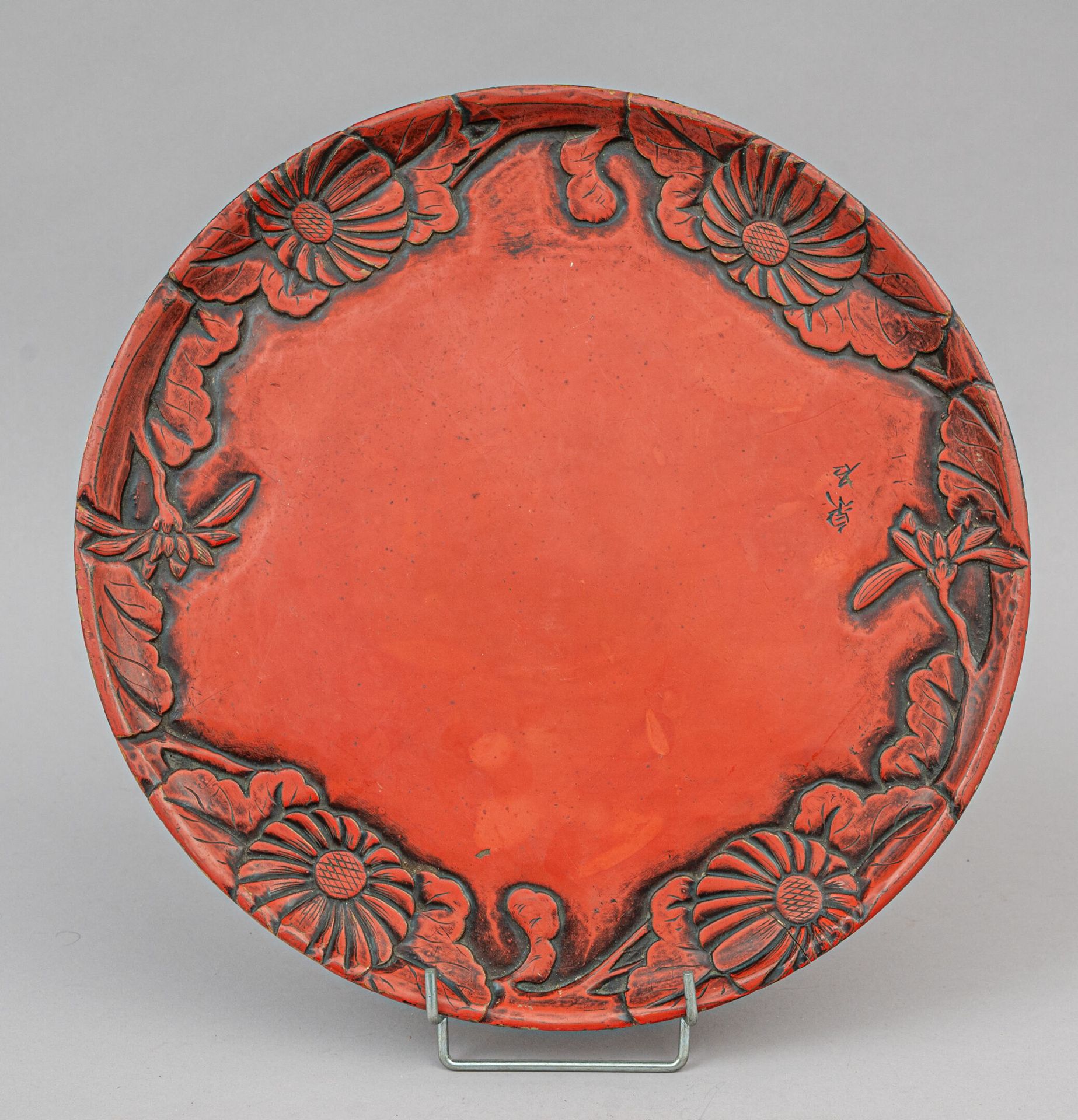 Null 红漆木盘，日本，20 世纪早期
圆形，边缘浮雕菊花和叶子，背面黑漆，顶部刻有签名。磨损、划痕、裂纹
直径 35 厘米
