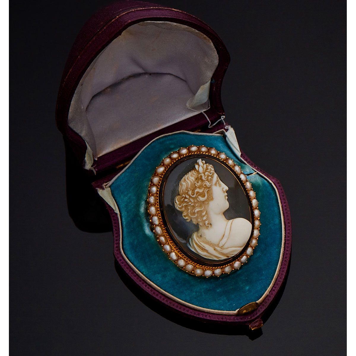 Null 18K黄金胸针，玛瑙上的浮雕代表一位年轻女性的轮廓，由黑色珐琅网衬托，周围有珍珠，装在其形状的盒子里。法国的工作。

B.P. 26,4g。- 高4,&hellip;