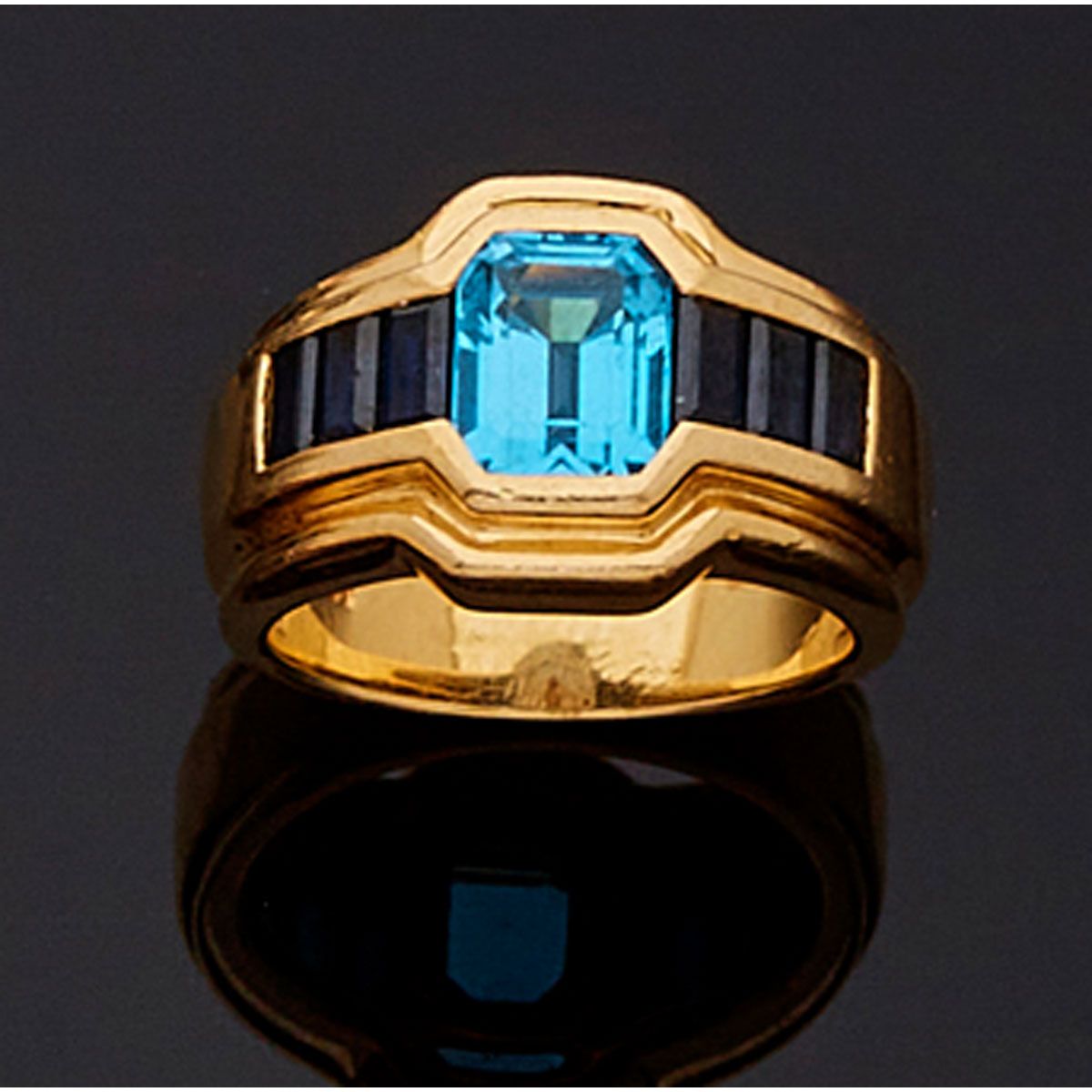 Null 一枚18K金戒指，镶嵌着一颗蓝色黄宝石和六颗长方形切割蓝宝石。法国的工作。

B.P. 13,6g。- TDD 54