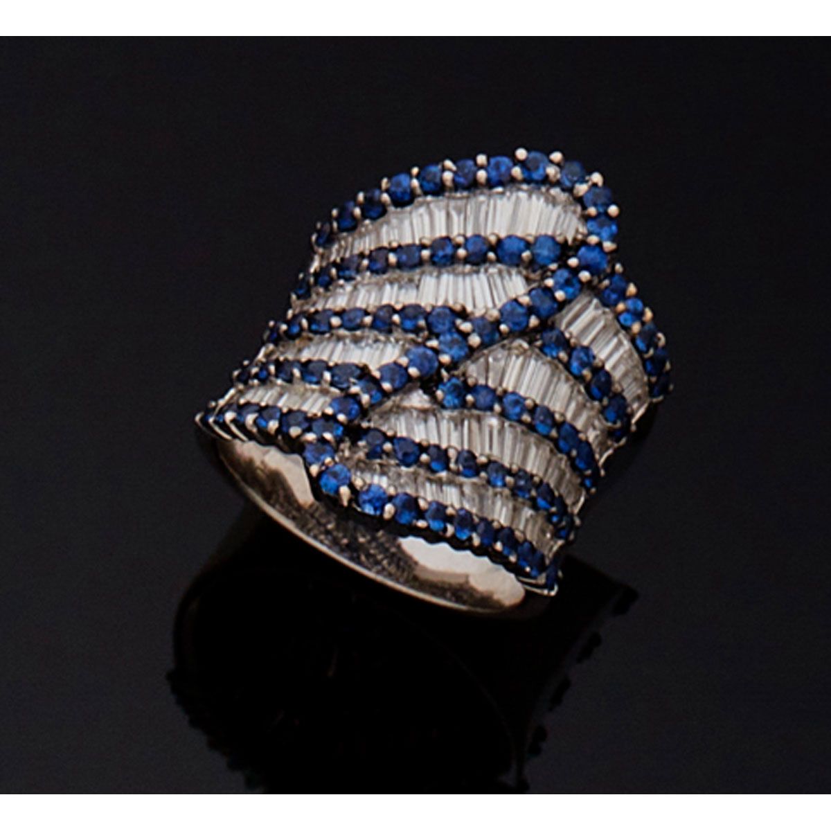 Null 18K白金鸡尾酒戒指，镶有四条重叠的长方形切割钻石，并以蓝宝石为亮点。

B.P. 14.6克。- TDD 55
