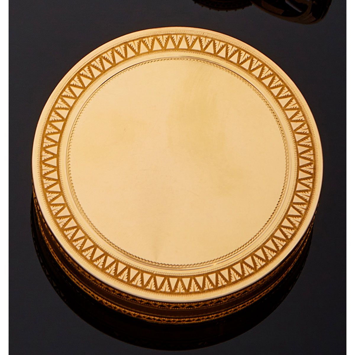 Null 18K黄金圆盒，两侧的扭索纹被几何装饰的花环所包围。1798年至1809年间，巴黎的第一只公鸡的标记。

B.P. 69,8g。- 直径62毫米