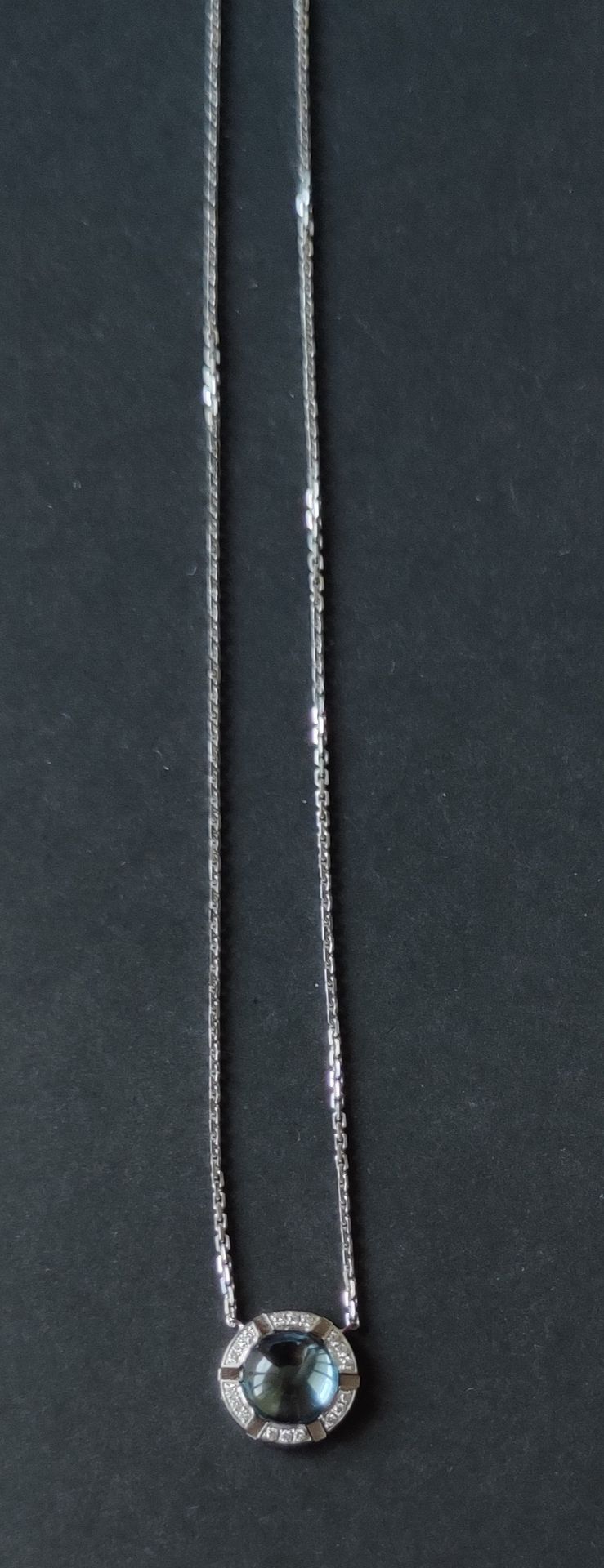 Null 巴黎CHAUMET

一条白金项链，链子支撑着一个圆形的图案，上面镶嵌着一颗凸圆形的蓝宝石，并有小的切割钻石，背面有标记和编号。

毛重：6.8克