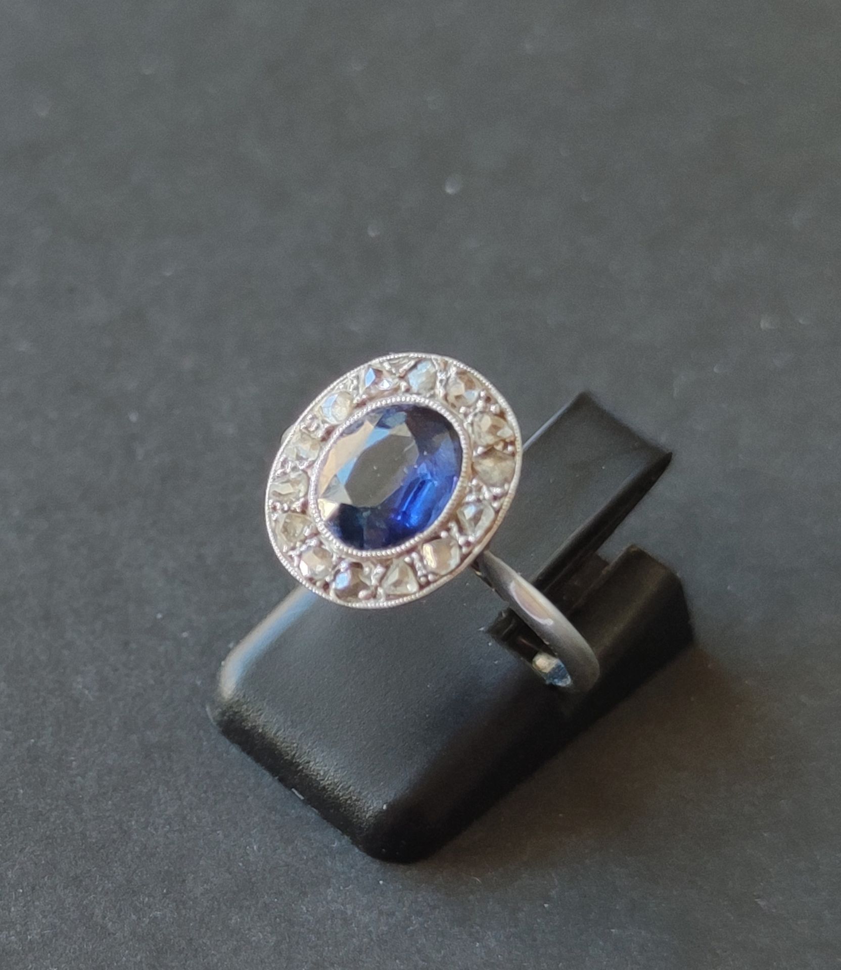 Null 
戒指，750°/°的白金镶嵌，在一圈小钻石中镶嵌一颗中央蓝宝石，经测试重2.6克（佩戴）手指尺寸：55 1/2