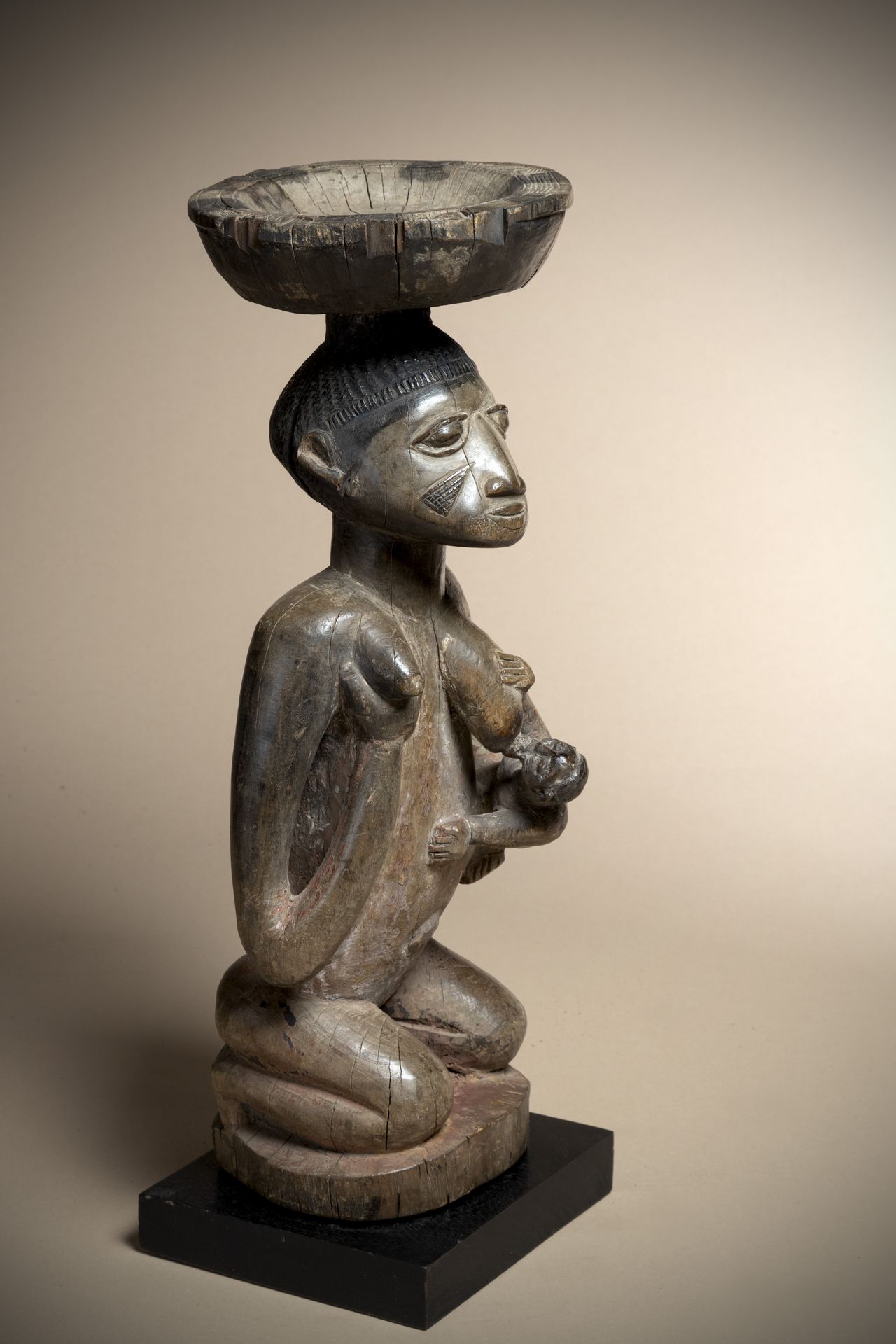 Null YORUBA (尼日利亚)

孕妇头上带着一个供品盘，呈跪姿，她抱着自己的右乳，而用左臂支撑着婴儿。沉重的木头，有淡淡的铜锈

高度：46厘米