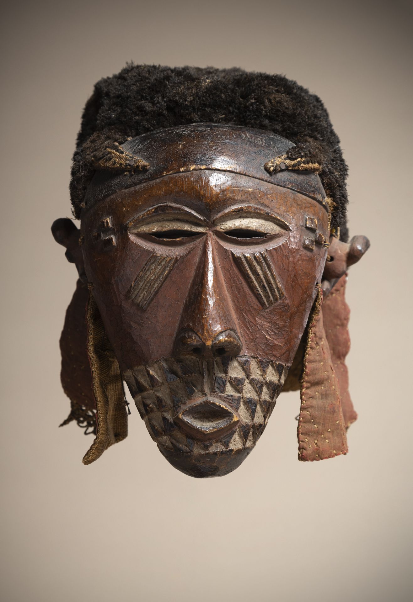 Null KUBA（刚果共和国）

多色面具，带着厚厚的酒椰叶的头饰。美丽的红褐色铜锈。木耳被缝在布制头饰的背面。

高度：27厘米