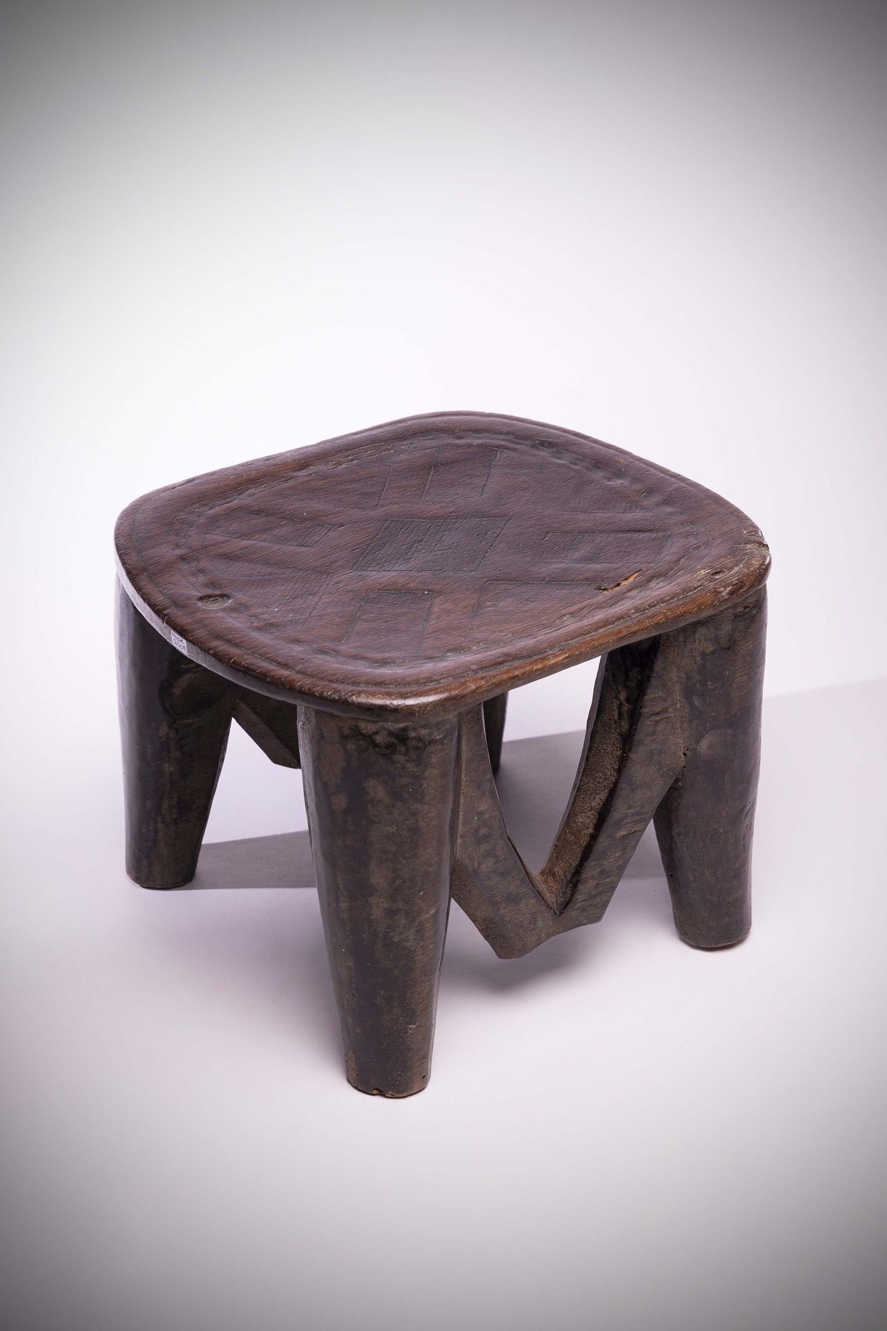 Null Nupé

(尼日利亚)重拍木制单层座椅，由四条腿支撑，以拱门连接。

顶部刻有几何图案。高：20厘米