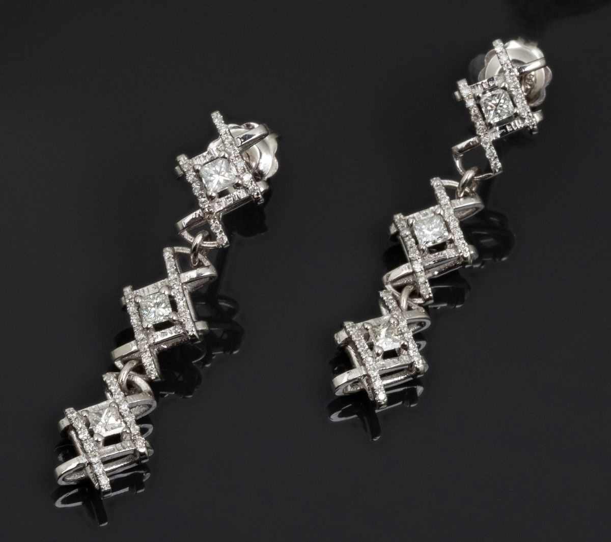 Null 一对18K白金（千分之七十五）吊坠耳环，在铺面线中呈现出美丽的纯度和颜色的公主切割钻石的交叉。它很形象，很有魅力!
长度：4厘米。
毛重：7,8克。