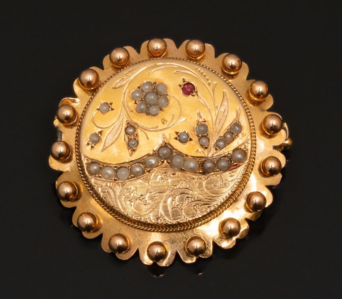 Null 18K黄金（千分之七十五）圆形胸针，装饰有仿珍珠和一个小型红色玻璃凸圆形的花卉图案。轮廓颗粒化。背面有焊接点。
直径：3.2厘米。
毛重：5.6克。