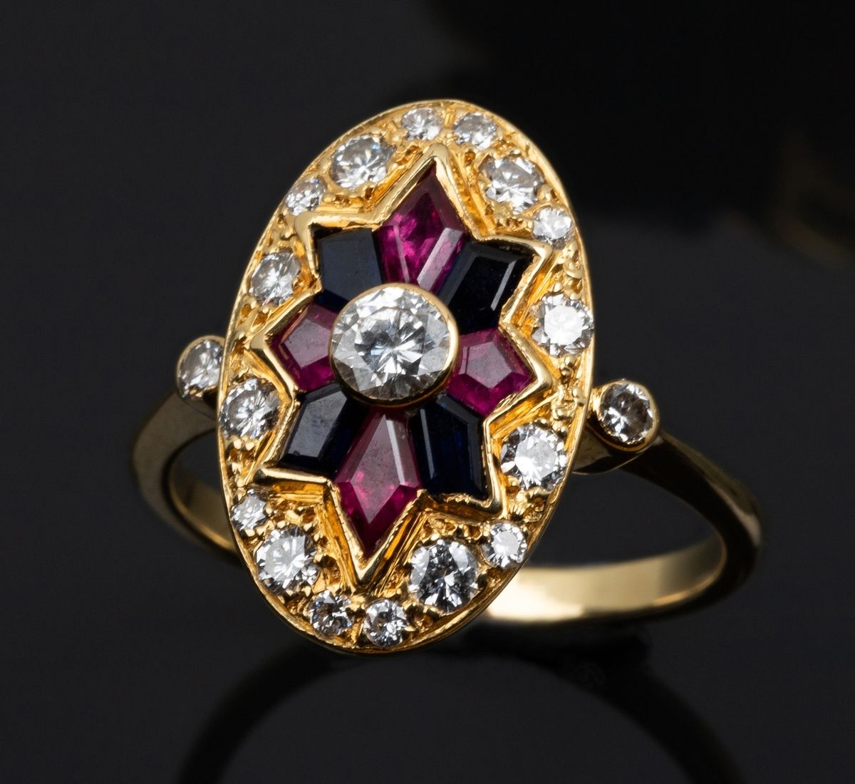 Null 18K黄金（千分之七十五）椭圆形戒指，在圆形明亮式切割钻石的铺垫下，镶嵌着红宝石和合成蓝宝石交替而成的星形图案。它很精致，做工精细。
手指大小：54
&hellip;