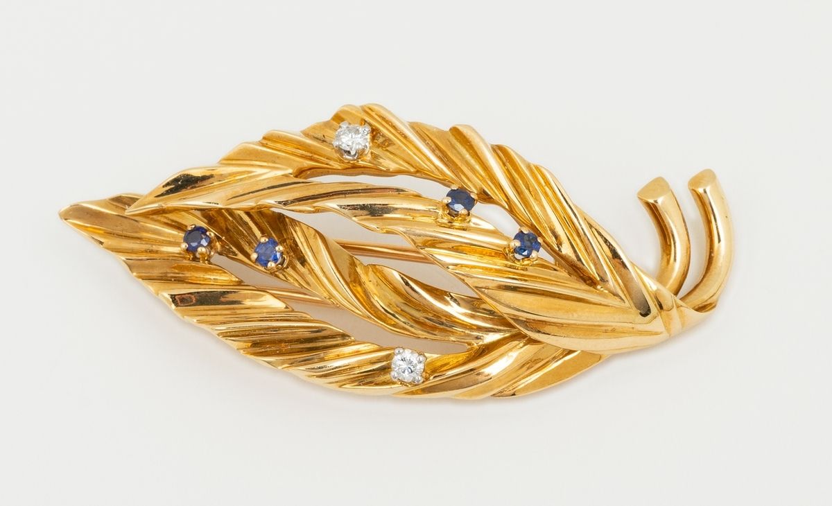 Null 一枚1940-1950年代的18K（750K）黄金胸针，表现了两片并列的、精巧的叶子，镶嵌了两颗圆形明亮型钻石和四颗小的改良圆形明亮型蓝宝石，可能是天&hellip;