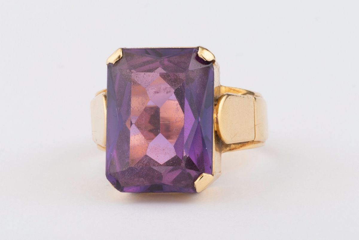 Null 20世纪50/60年代的18K黄金（千分之七十五）鸡尾酒戒指，镶有一颗合成紫色蓝宝石（小碎片）。肩部有图形曲线。石头需要收紧。 
手指尺寸：57
毛重&hellip;