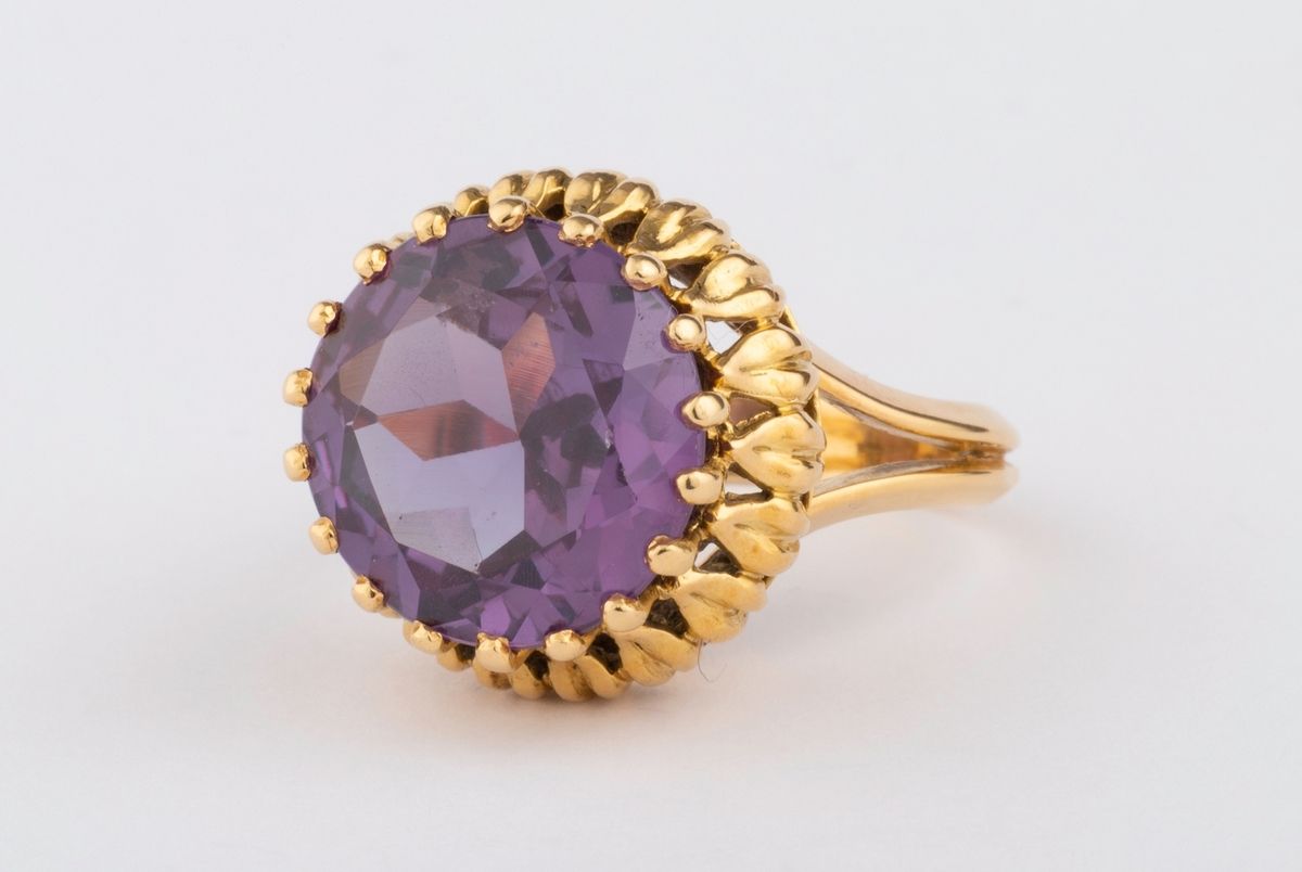 Null 一枚20世纪50年代的18K（750K）黄金戒指，V型肩和迷人的篮子工作，持有一颗紫红色的圆形合成蓝宝石。
宝石的尺寸：13.57 - 13.64 x&hellip;
