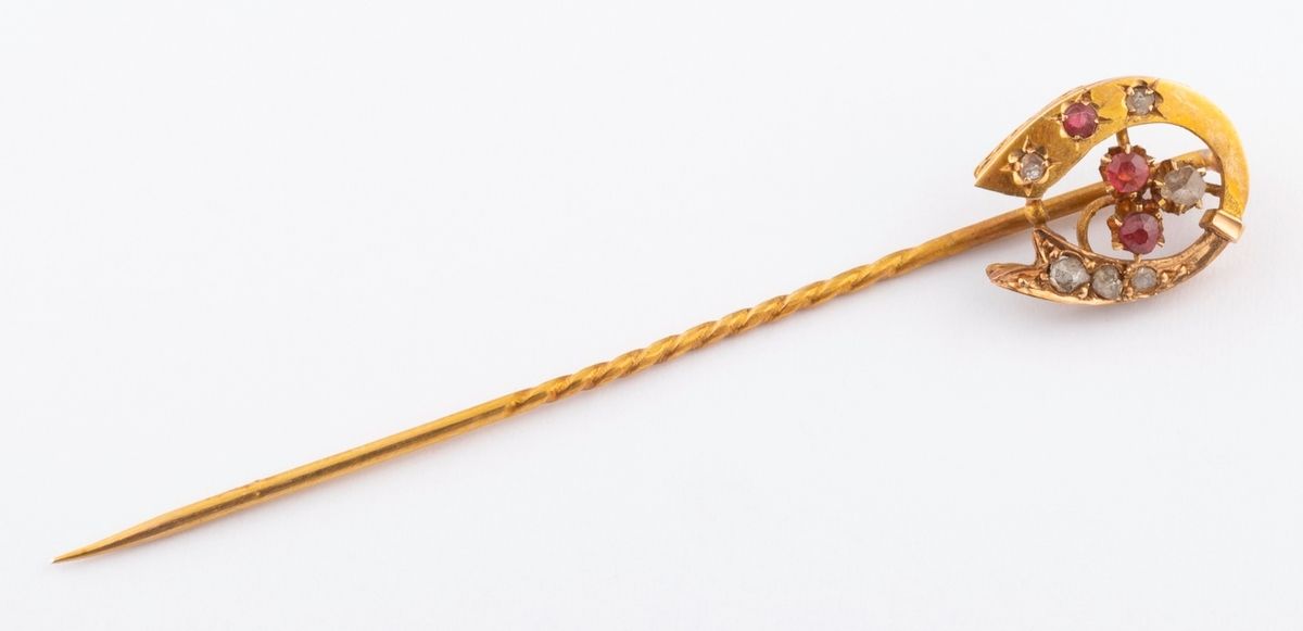Null 18K（750千分之一）黄金拉瓦列尔针，上面有一个马蹄形，上面有钻石碎片和红色玻璃装饰。 
长度：6.2厘米。 
毛重：1.7克。