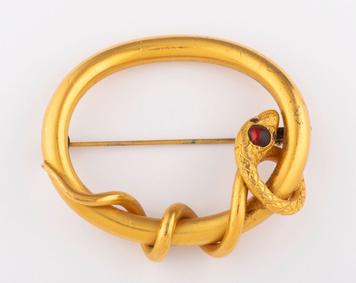 Null 来自19世纪的美丽的蛇形胸针，采用精雕细琢的鎏金金属。头部和眼睛装饰有红色玻璃凸圆形。 
尺寸：5.7 x 5厘米。 
毛重：26克。