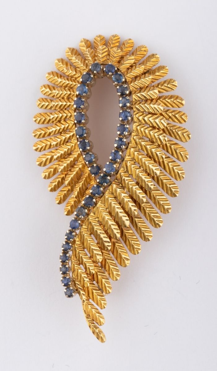 Null 18K（千分之七十五）黄金的双层羽毛胸针，镶有一圈小型圆形明亮式切割处理的蓝色蓝宝石。意大利生产。 
尺寸：5.4 x 2.7厘米。 
毛重：13克。
